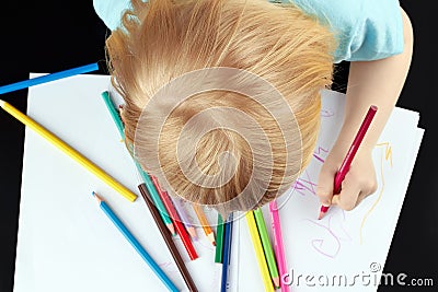 Blond girl is drawing by pencil