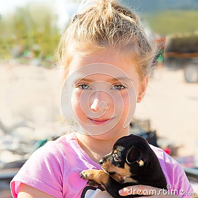 Blond kid girl playing with puppy dog smiling