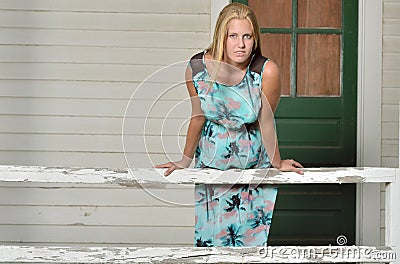 Blonde fashion model poses near shuttered house