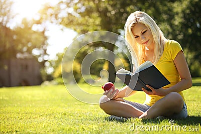 Blonde Girl with Book and Apple on Green Grass.