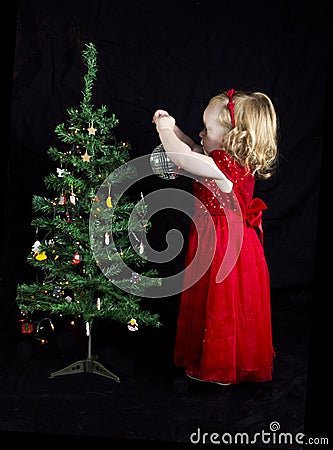 Blonde girl with red dress decorating christmas tree