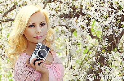 Blonde Girl with Retro Camera over Cherry Blossom.