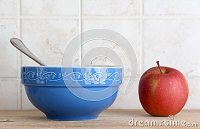 A blue ceramic cup with a spoon and an apple
