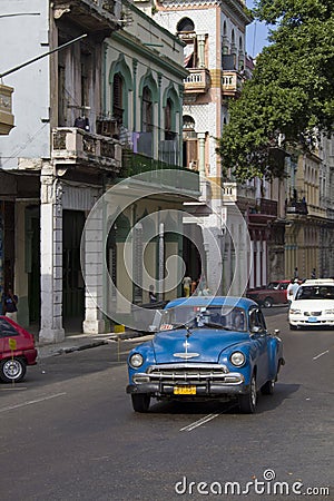 Blue classic car driving down old Cuban street