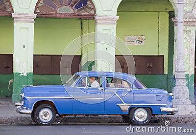 Blue Classic Cuban car and dilapidated building
