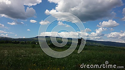 Blue sky, puffy clouds and green terrain