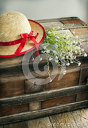 Blue summer flowers and straw hat on vintage chest