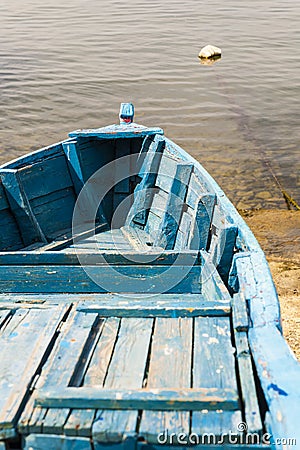 Blue wooden rowing boat on lake. Blue paint on boards.