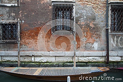 Boat docked to a house wall in a canal at Venice, Italy