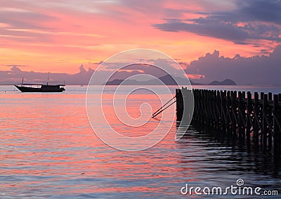 Boat and jetty on sunset sea