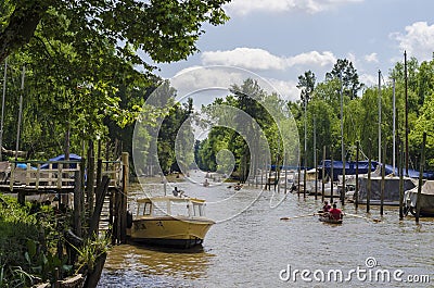 Boat in pier, and several canoes rowing along canal in Tigre, Buenos Aires