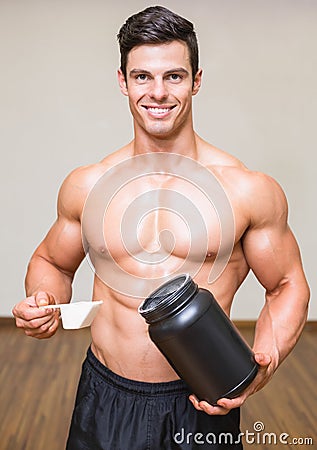 Body builder holding a scoop of protein mix in gym