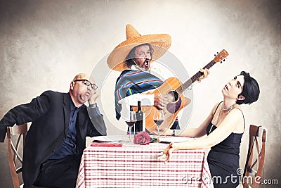 Bored couple at dinner oblyed to listen to a mexican musician