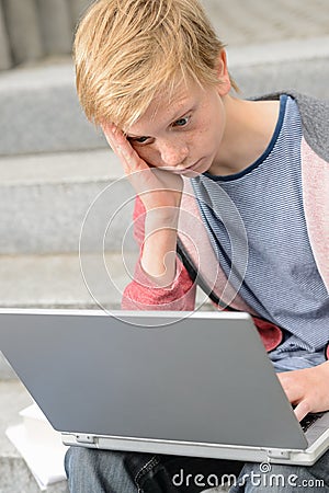 Bored teenage student using laptop