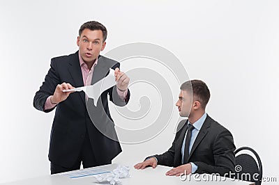 Boss angry with young employee sitting at desk