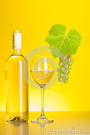 Bottle and glass of white wine with grape cluster