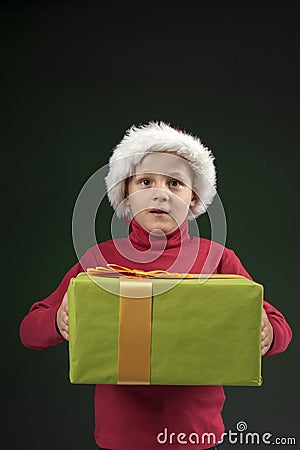 Boy with christmas hat and present on dark green