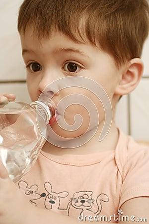 The boy drinks water from a bo