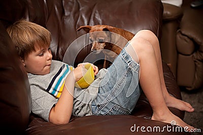 Boy eating cereal with little dog watching
