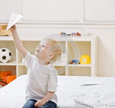 Boy flying paper airplane in bedroom