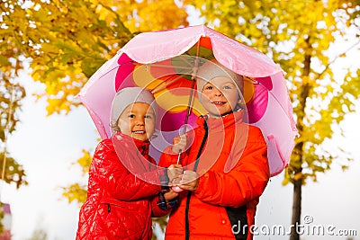 Boy and girl hold umbrella together under rain