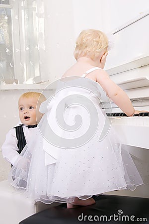 Boy and girl playing on a white piano