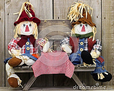 Boy and girl scarecrows sitting at picnic table with blank rustic wood sign