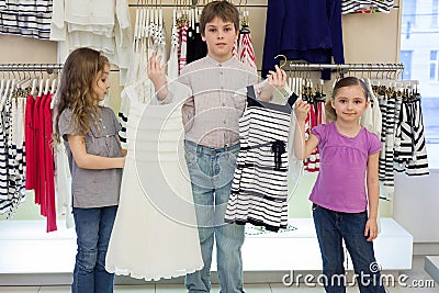 The boy helps cute girls to choose dress in shop