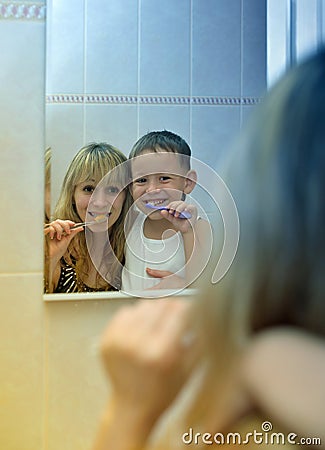 Boy with his mother to brush their teeth in front of mirror