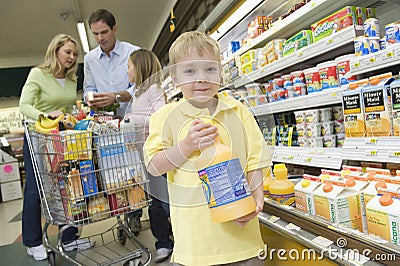 Boy Holding Orange Juice With Family In Supermarket