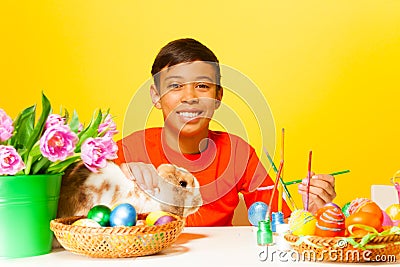Boy paints Easter eggs with rabbit on the table