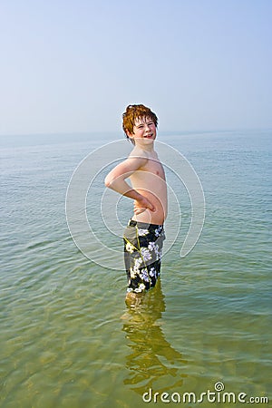 Boy with red hair stands in the ocean