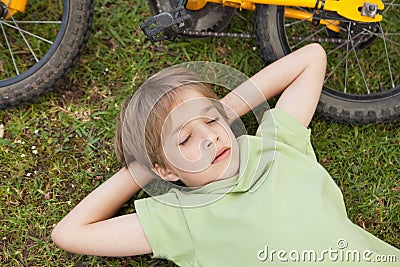 Boy resting besides bicycle at park