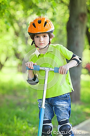 Boy in a safety helmet stands with kick scooter