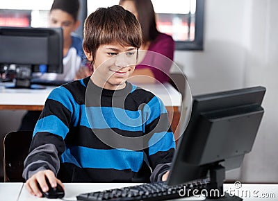 Boy Smiling While Using Computer In Classroom