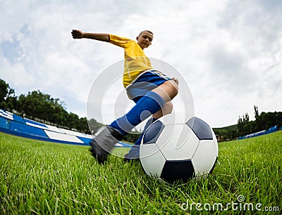 Boy soccer player hits the football ball