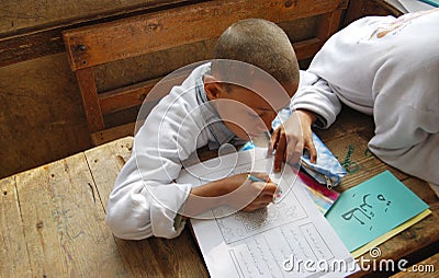 A boy studying and writing homework in arabic