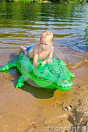 Boy swimming in the river with inflatable crocodile