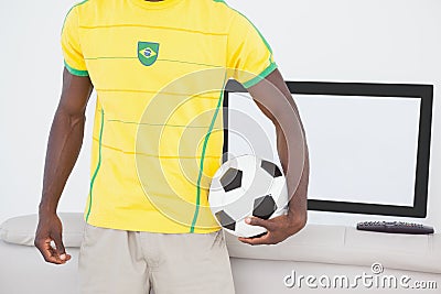 Brazilian fan holding ball in front of tv