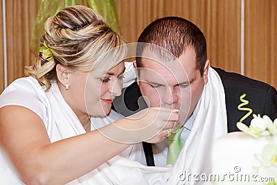 Bride feeding her groom with spoon on wedding lunch