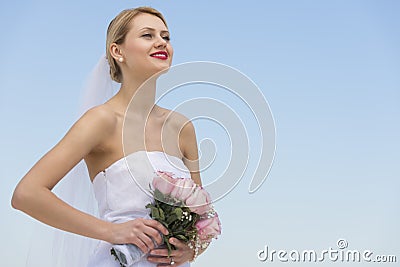 Bride With Flower Bouquet Looking Away Against Clear Blue Sky
