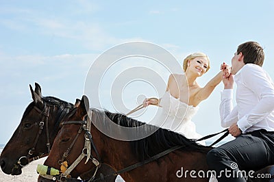 Bride and groom on a horses by the sea