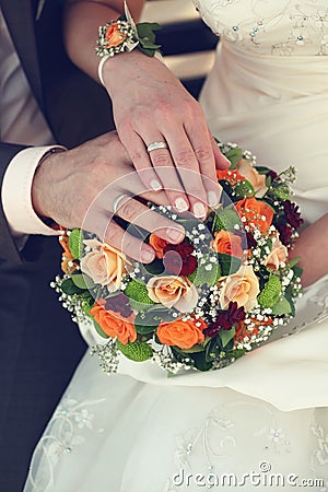 Bride and groom s hands with wedding rings and bouquet