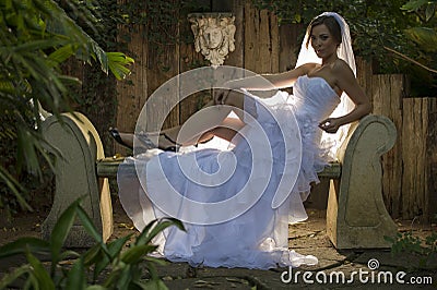 A bride with hairlight sitting on a concrete bench