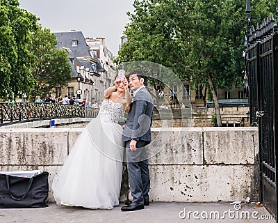 Bride takes a selfie of herself and her groom at the Pont de l Archeveche, Paris