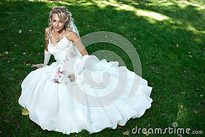 Bride in white dress on green grass