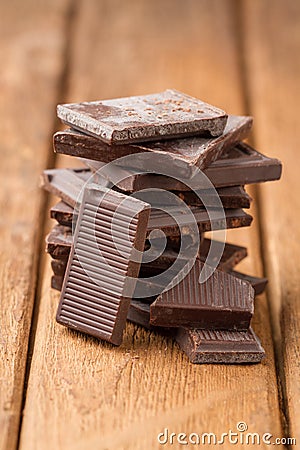 Broken dark chocolate bar on a wooden table