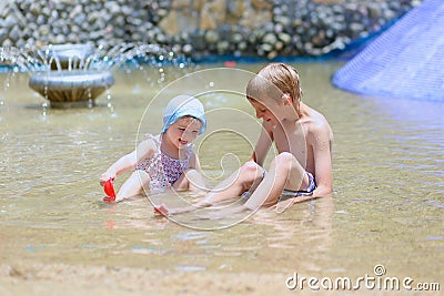 Brother and sister playing in outdoors swimming pool