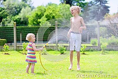 Brother and sister playing with water hose in the garden