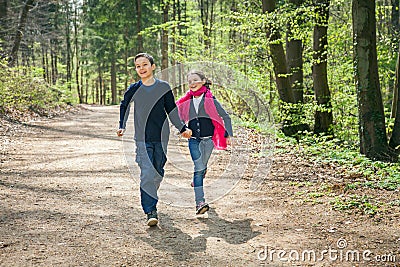 Brother and Sister running in a forest hand in hand